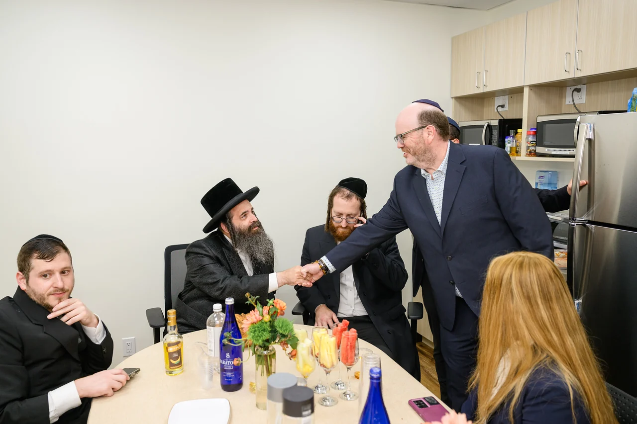 Guests greet one another around a table at the Monsey opening.