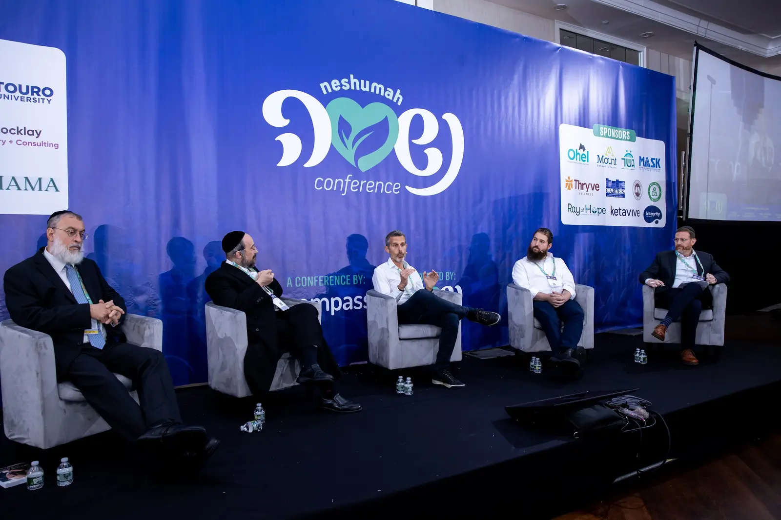 Professionals speaking together on the Neshumah Conference stage